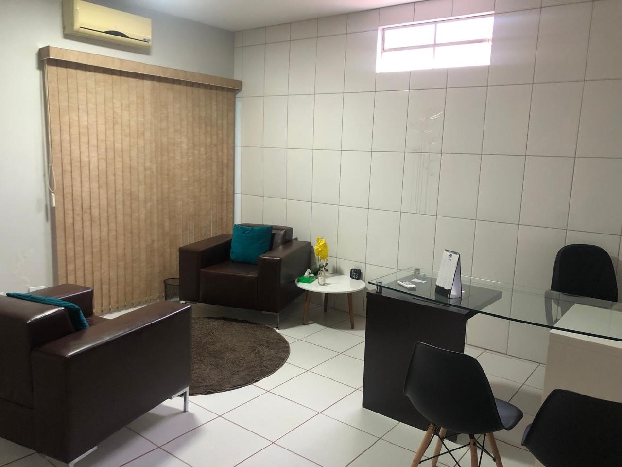 Sala de atendimento com poltronas marrons, mesa de vidro e ar-condicionado