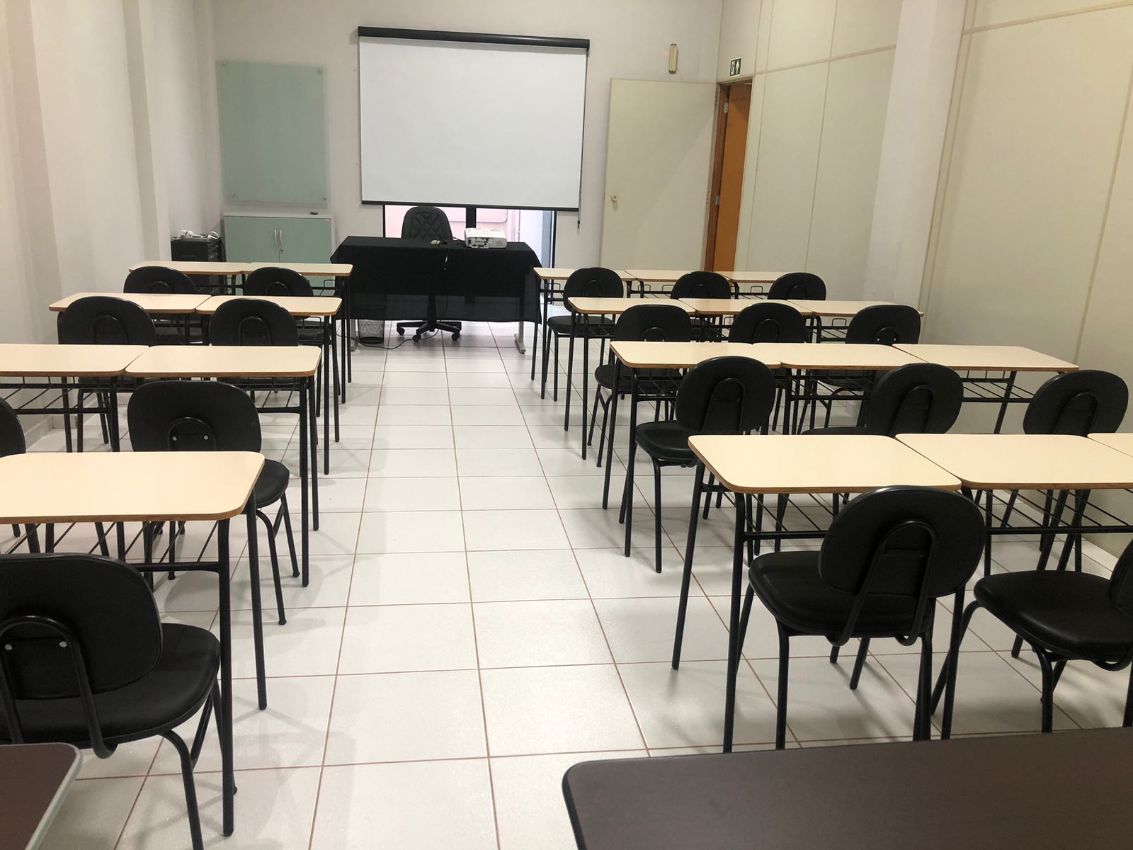 Sala de aula com carteiras individuais, projetor e tela de projeção