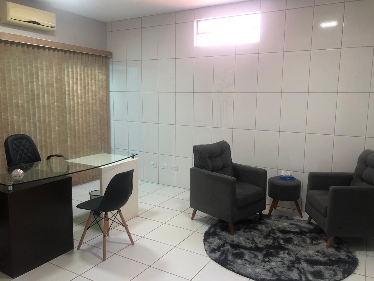 Sala de atendimento com mesa de vidro, poltronas cinza e ar-condicionado